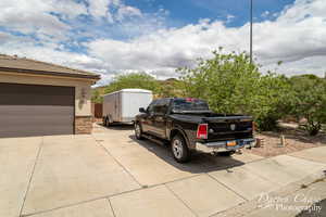 View of property exterior with stucco siding, a tile roof, driveway, and stone siding