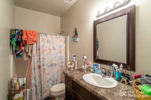 Bathroom featuring toilet, vanity, a shower with shower curtain, and visible vents
