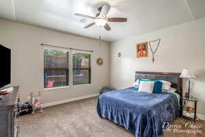 Carpeted bedroom featuring baseboards, a ceiling fan, and visible vents