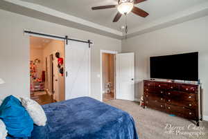 Bedroom featuring a ceiling fan, baseboards, carpet floors, and a barn door