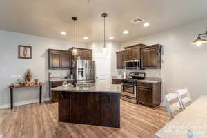 Kitchen featuring dark brown cabinets, light wood-type flooring, visible vents, and stainless steel appliances