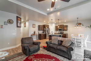 Living room with recessed lighting, baseboards, ceiling fan with notable chandelier, and light wood-type flooring