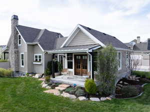 Back of house with a lawn, a chimney, french doors, metal roof, and a standing seam roof
