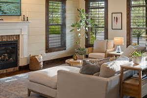 Living area with a tile fireplace, wood finished floors, and a wealth of natural light