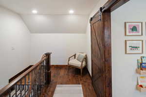 Corridor featuring lofted ceiling, recessed lighting, dark wood-type flooring, and a barn door