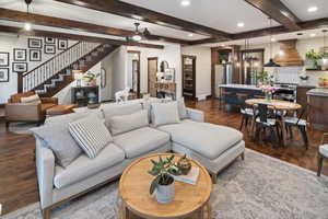 Living room with a ceiling fan, stairs, beamed ceiling, dark wood-style flooring, and recessed lighting
