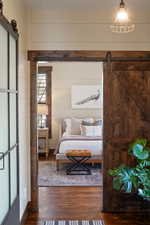Bedroom featuring wooden walls, wood finished floors, and a barn door