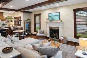 Living area with baseboards, beamed ceiling, dark wood-style floors, and plenty of natural light
