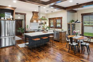 Kitchen featuring custom exhaust hood, dark wood finished floors, appliances with stainless steel finishes, and a kitchen island