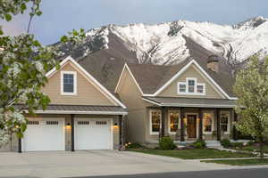 Craftsman-style home featuring a standing seam roof, a mountain view, driveway, covered porch, and metal roof
