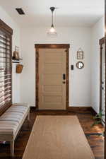 Entryway featuring dark wood-style floors, baseboards, and visible vents