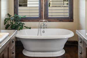 Bathroom featuring a freestanding bath, vanity, and wood finished floors