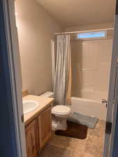 Bathroom with toilet, shower / bath combo, vanity, and a textured wall