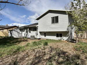 Rear view of house with fence and central AC
