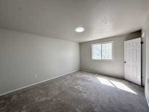 Carpeted spare room featuring baseboards