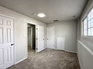 Unfurnished bedroom featuring baseboards, carpet flooring, and visible vents