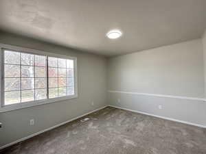 Carpeted empty room featuring baseboards and visible vents