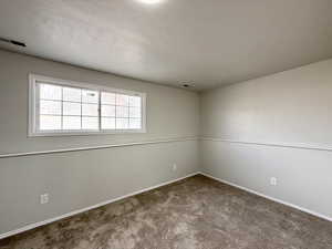 Unfurnished room with baseboards, visible vents, carpet, and a textured ceiling