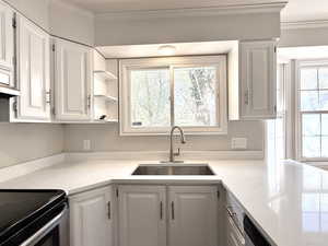 Kitchen featuring white cabinets, crown molding, and a sink