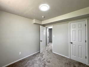 Unfurnished bedroom featuring carpet floors, a textured ceiling, and baseboards