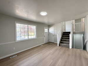 Entrance foyer with wood finished floors, visible vents, baseboards, and stairway