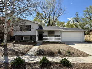 Tri-level home with a garage, driveway, a porch, and fence