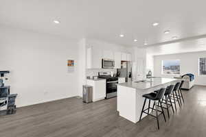 Kitchen featuring wood finished floors, a breakfast bar area, stainless steel appliances, and a sink
