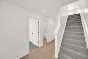 Stairway featuring baseboards, wood finished floors, visible vents, and recessed lighting