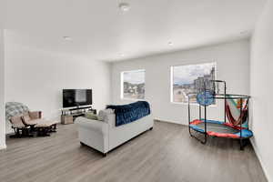 Living area with baseboards, a healthy amount of sunlight, and light wood finished floors