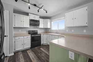 Updated kitchen with wood look flooring, white cabinets, and black stainless steel appliances.