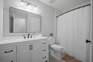 The updated hall bathroom includes farmhouse style white cabinets, updated flooring, lighting and tub surround.