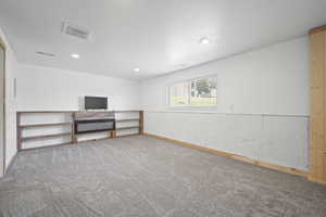 Lower level family room with built-in bookshelf, electric fireplace and brand new carpet.