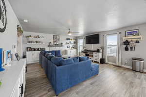 Living area featuring light wood-style flooring, a textured ceiling, a ceiling fan, and baseboards