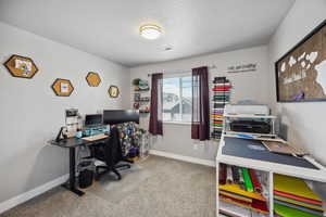 Office with a textured ceiling, carpet, visible vents, and baseboards