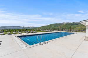 Community pool featuring a patio, fence, and a mountain view