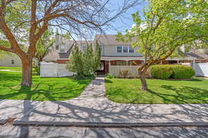 View of front of home with a chimney, fence, a shingled roof, brick siding, and a front yard