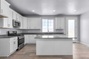Kitchen featuring a sink, stainless steel appliances, light wood-style flooring, white cabinets, and recessed lighting