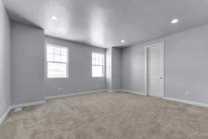Carpeted spare room featuring baseboards, a textured ceiling, and recessed lighting