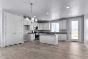 Kitchen featuring dark countertops, baseboards, appliances with stainless steel finishes, and light wood-style floors