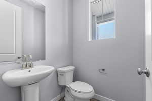 Half bath with baseboards, a sink, and toilet