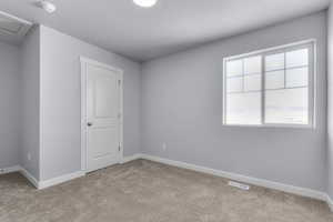 Carpeted empty room featuring attic access, baseboards, and visible vents