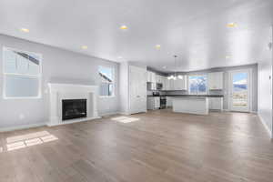Unfurnished living room with recessed lighting, an inviting chandelier, light wood finished floors, and baseboards