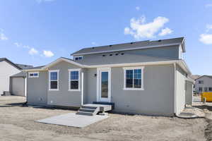 Rear view of house with stucco siding and roof with shingles