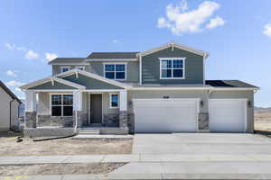 Craftsman-style house featuring an attached garage, driveway, stone siding, and stucco siding