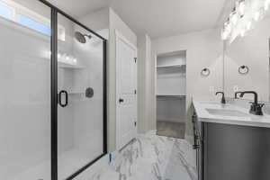 Full bathroom featuring double vanity, marble finish floor, a stall shower, and a sink