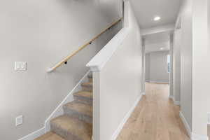 Staircase featuring baseboards, hardwood / wood-style floors, and recessed lighting