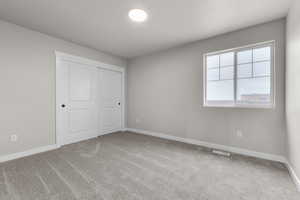 Unfurnished bedroom with carpet floors, a closet, and baseboards