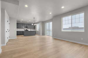 Kitchen featuring light countertops, baseboards, appliances with stainless steel finishes, and open floor plan