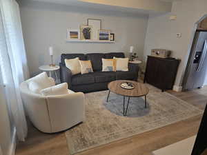 Living room featuring visible vents, baseboards, arched walkways, and wood finished floors