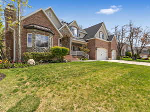 View of front of home featuring a porch, a front lawn, concrete driveway, and stone siding